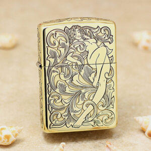 Gold Zippo lighter with an ornate black engraving of a reclining nude woman among swirling floral patterns.