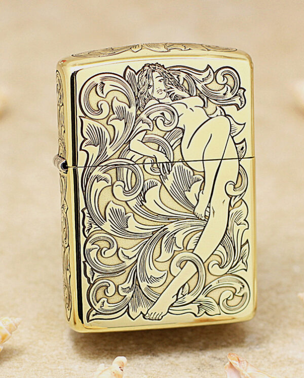 Gold Zippo lighter with an ornate black engraving of a reclining nude woman among swirling floral patterns.