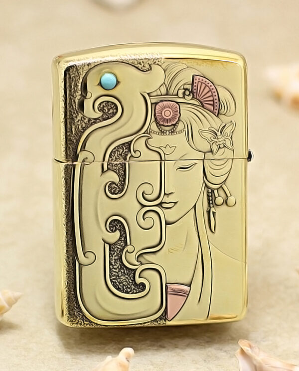 Gold-toned Zippo-style lighter with an Art Nouveau design featuring a woman's face and swirling patterns.