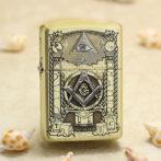 Gold Zippo lighter with Masonic symbols (eye in triangle, compass and square with G) displayed on a sandy beach with seashells nearby.