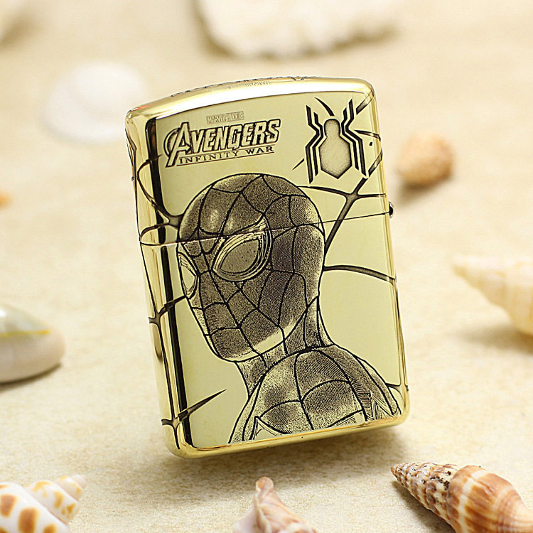 Gold metal lighter featuring Spider-Man drawing and Avengers: Infinity War logo on a sandy beach background.