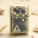 Brass Zippo-style lighter with a honeycomb hexagon pattern and a danger symbol on the front.