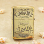 Gold Zippo-style lighter with 'WIDES' branding and a skyline illustration on the front, resembling a mosque and palm trees.