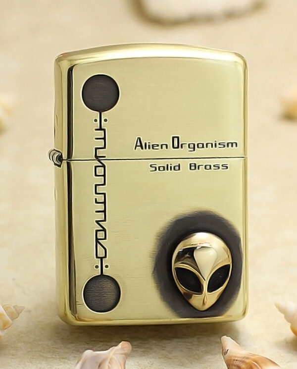 KZ253 Brass lighter with engraved text 'Alien Organism' and 'Solid Brass' and a small alien head emblem on the front.