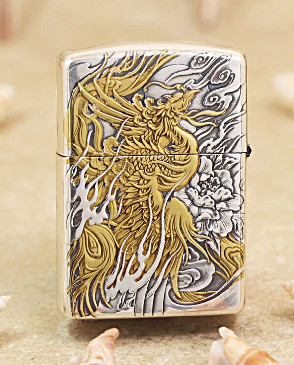 KZ282-01 Silver Zippo-style lighter with a detailed gold dragon engraving on a gray background, resting on sand with scattered seashells nearby.