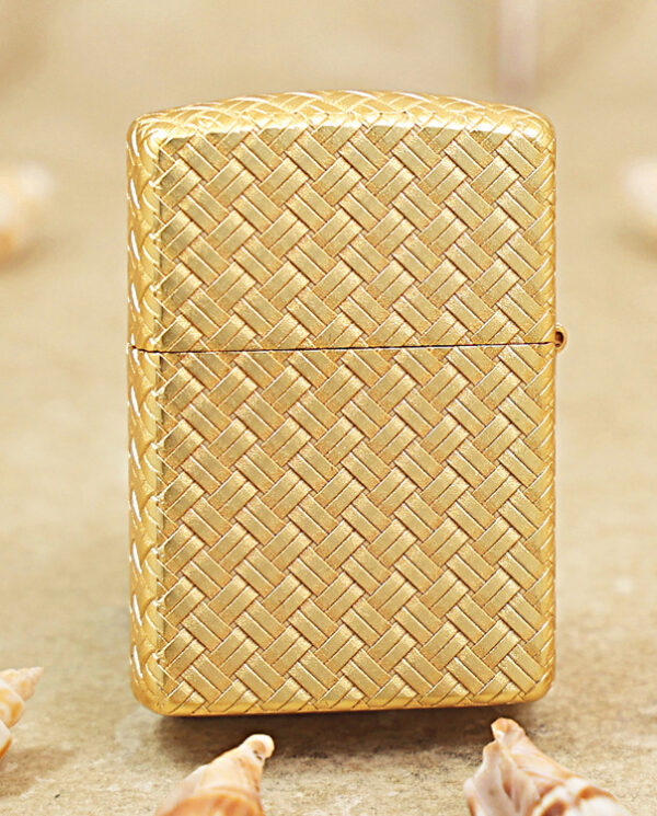 KZ284-01 Gold woven-pattern lighter standing upright on a sandy surface with seashells around.
