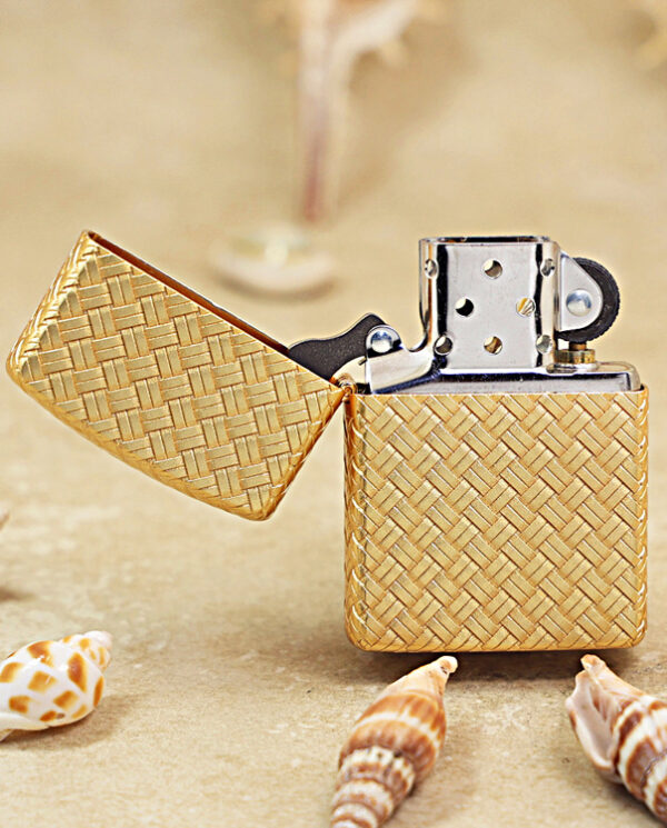 KZ284-02 Gold patterned lighter with the lid open, resting on sand near seashells.