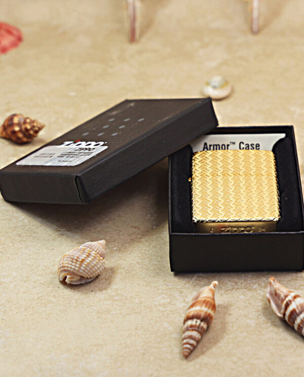 KZ284-06 Gold textured Zippo lighter in a black box labeled Armor Case on a sandy beach with seashells.