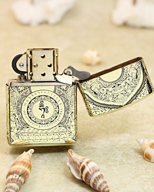 KZ304-03 Ornate vintage metal lighter with open lid on sandy beach, surrounded by seashells.