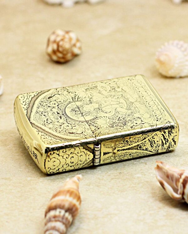KZ304-04 Ornate gold cigarette case with intricate engravings resting on sand among seashells.