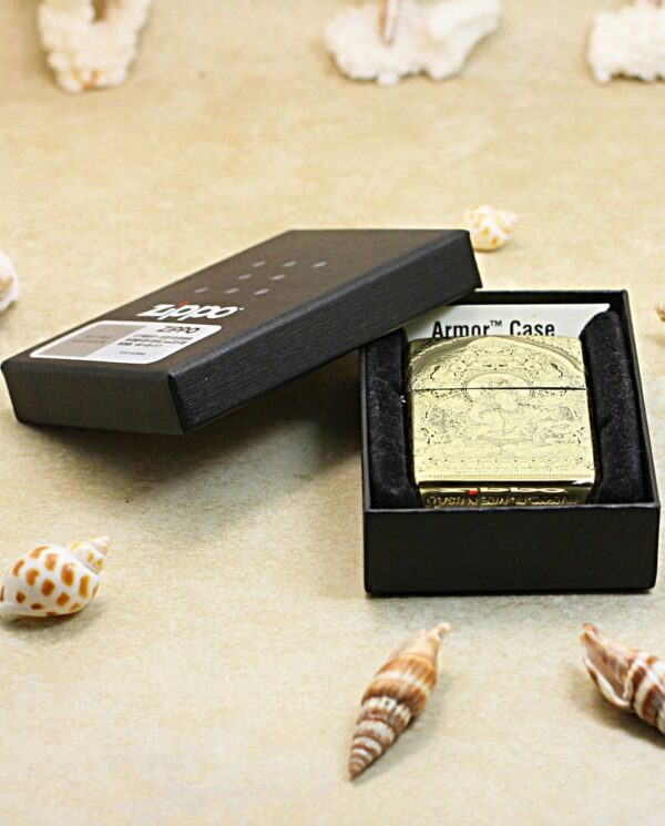 KZ304-06 Ornate gold lighter in a black box on a sandy surface with seashells around.