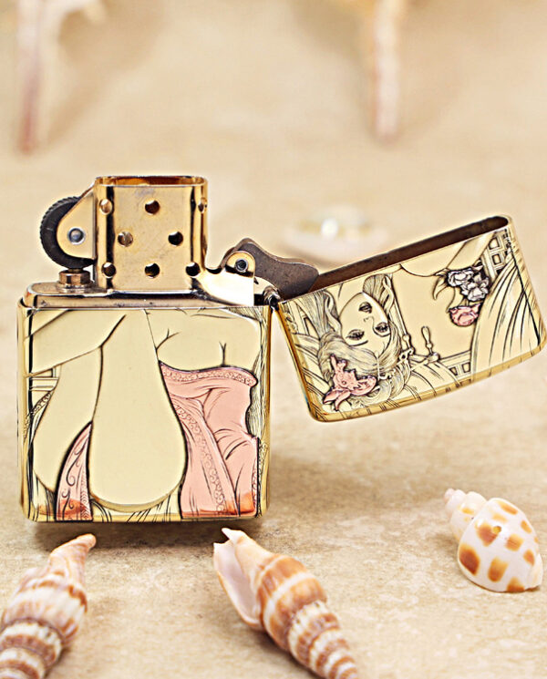 KZ426-03 Gold metal lighter with colorful pin-up girl artwork on its sides, open lid, resting on a sandy surface with seashells nearby.