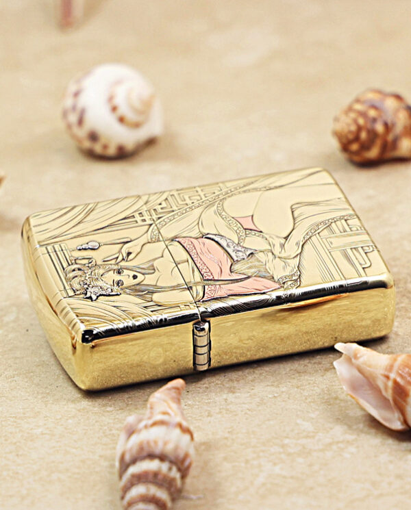 KZ426-04 Gold-toned metal lighter with an engraved image of a woman in traditional dress, resting on sand among seashells.