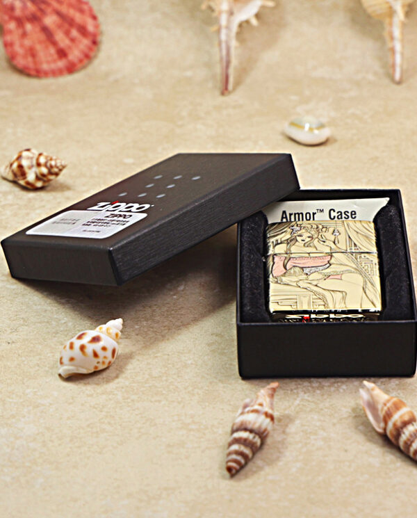 KZ426-06 Gold engraved lighter in an open black box on a sandy surface with seashells surrounding it.