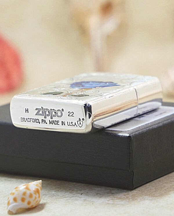 KZ461-05 Shiny Zippo lighter resting on a black box, showing 'Zippo' and 'Made in U.S.A.' on its base with decorative engraving nearby.