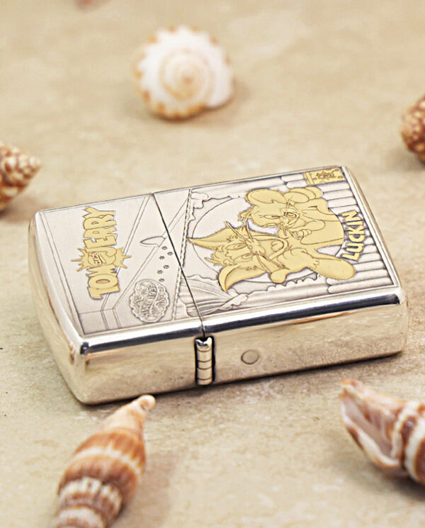 Metal Zippo lighter on sand with seashells, featuring Toy Story Woody design.