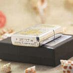 Shiny Zippo lighter resting on a black box with seashells around, showing engravings and 'Made in USA' text on the base