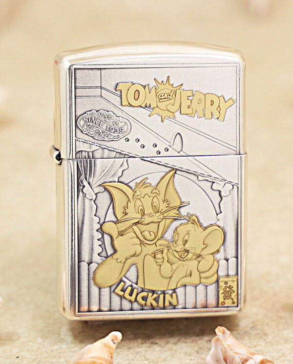 Metal Zippo lighter with a Tom and Jerry cartoon on the front, showing Tom and Jerry posing together with the 'Tom and Jerry' label at the top and 'LUCKIN' text at the bottom.