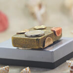 Brass Zippo lighter with coins attached, resting on a gray gift box.