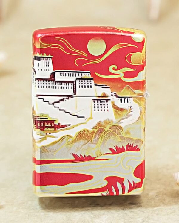 Decorative lighter with a red top featuring a white hillside town, mountains, and a sun motif in gold and white accents.