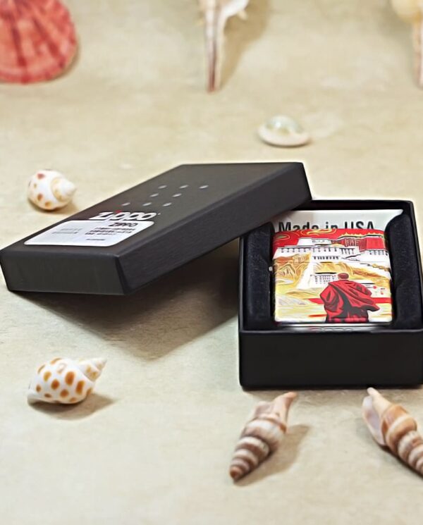 Open black gift box showing a colorful rectangular keepsake inside, with 'Made in USA' text, placed among seashells on a light surface.