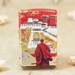 Decorative red-and-white box featuring a monk in a red robe overlooking a stylized temple scene.