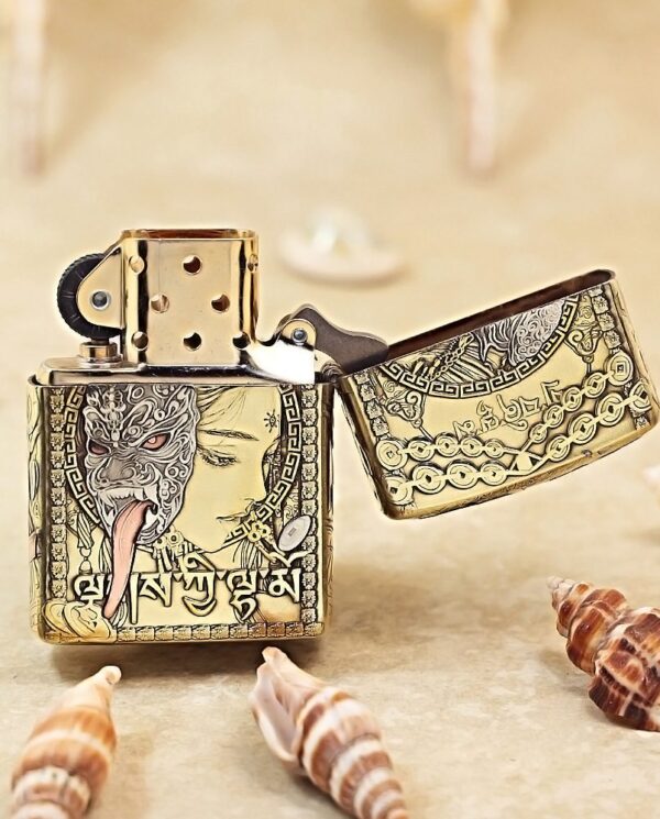 KZ501-03 Gold engraved Zippo-style lighter with an ornate design and a woman's profile, lid open, on a sandy surface with seashells nearby.