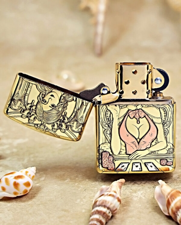 Gold Zippo lighter open to reveal a cartoon-style scene of a woman at a poker table with cards and chips, seashells around.