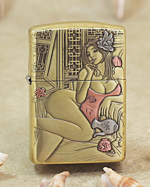 KZ510 Gold-tone Zippo lighter with an engraved art-deco image of a lounging woman in a pink swimsuit and flower in her hair, set among decorative patterns.