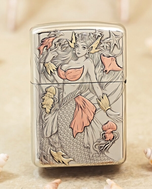 Metal lighter with an engraved mermaid design, pink-orange accents and sea-life details on a silver surface.