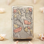 Metal lighter with a detailed mermaid illustration in pale pink and gold tones, other sea motifs around her.