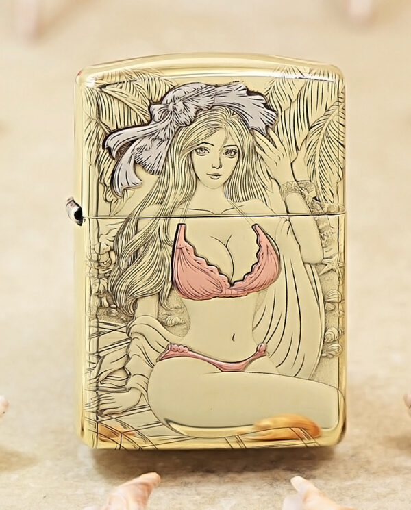 Gold-toned lighter with a pink bikini-clad illustrated woman among tropical leaves on the front surface.