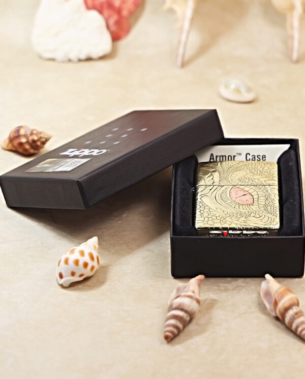 KZ371-06 Gold, textured Armor Case in an open black box, surrounded by seashells on a beige surface (product photo).