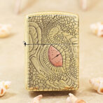 Gold Zippo lighter with a cracked, lace-like engraving and a pink teardrop centerpiece.