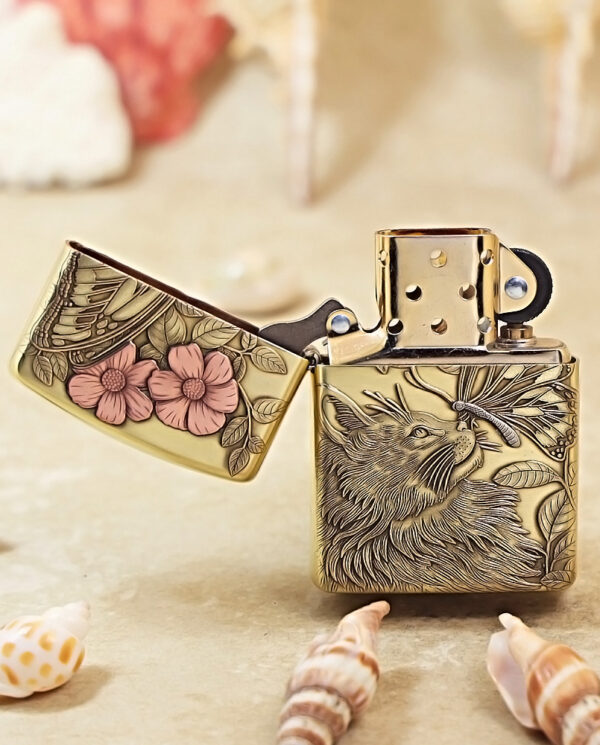 KZ135-02 Ornate brass lighter with wolf engraving, lid open, surrounded by seashells on a sandy surface.