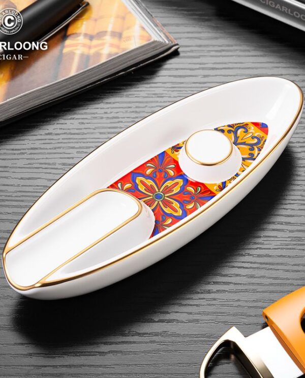 CL016-01 White ceramic boat-shaped ashtray with a colorful floral inlay and gold trim, brand logo visible in the corner.