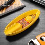 Yellow cigar lighter with a floral patterned inlay, placed on a dark wooden surface (brand Cigarloong visible).