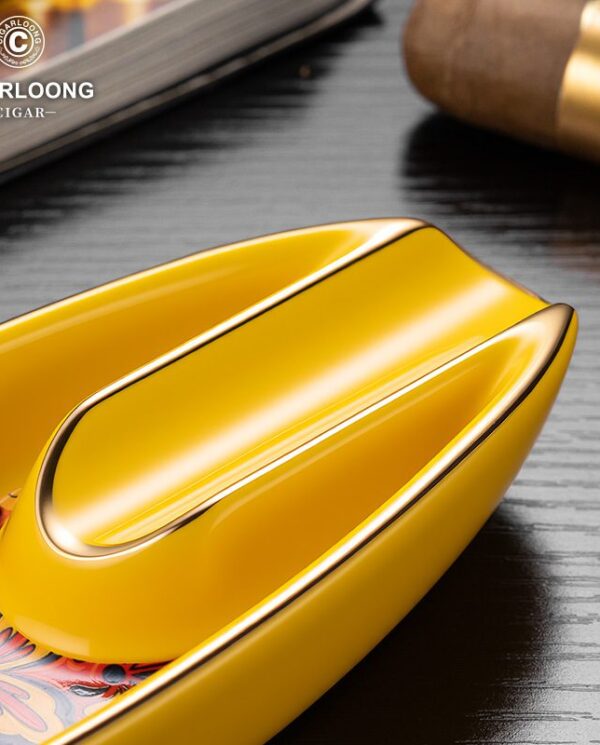CL016-07 Close-up of a bright yellow, glossy cigar ashtray with a curved groove on a floral-pattern tray; CigarLoong logo visible in the corner.