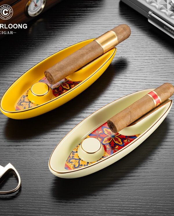 CL016 Two decorative boat-shaped cigar trays with colorful patterned interiors, each holding a cigar, visible with a lighter and accessories nearby; brand logo CIGARLOONG in the top left.