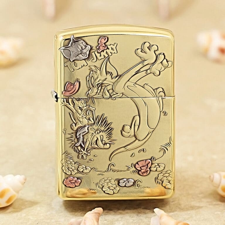 Gold-tone Zippo-style lighter with an engraved Tom and Jerry scene in a garden, showing Tom, Jerry, and flowers