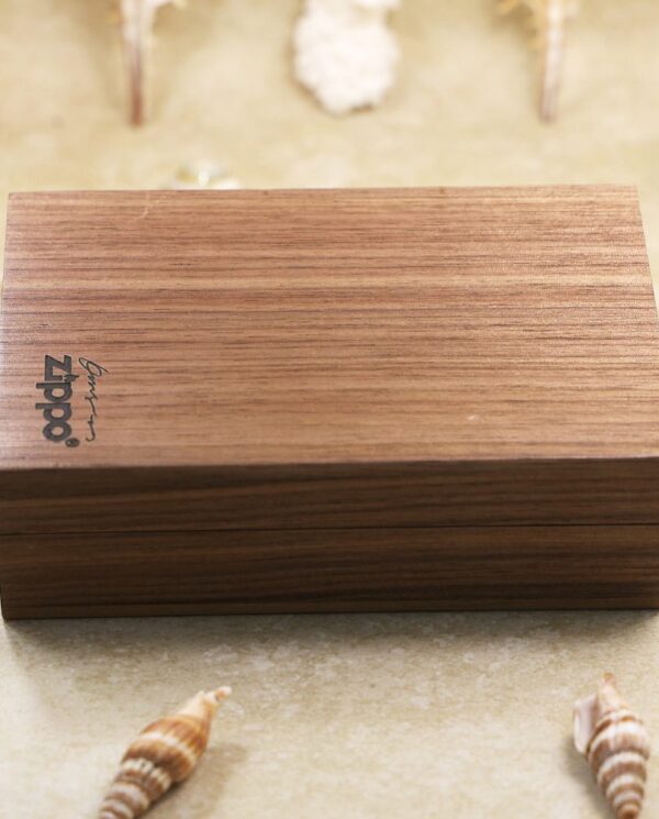 KZ127-07 Rectangular walnut wood jewelry box with a closed lid, placed on a sandy surface among seashells.