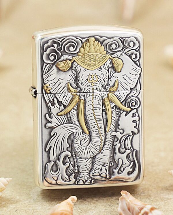 KZ127 Metal Zippo lighter with an embossed elephant design in gray and gold accents, standing among seashells on a sandy surface.
