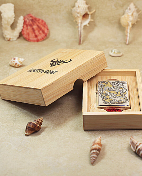 KZ136-05 Boxed Zippo lighter in a light wood display box on a sandy shell backdrop with shells around it