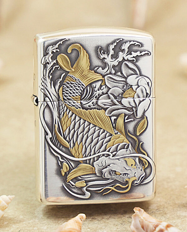 KZ136 Metallic lighter with a raised gold-and-silver koi fish design, surrounded by waves and flowers on a sandy surface.