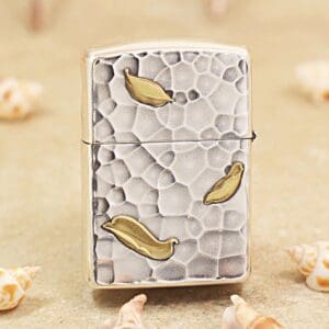 KZ148-01 Metallic lighter with a textured, pebble-like surface and gold leaf accents on a sandy background.