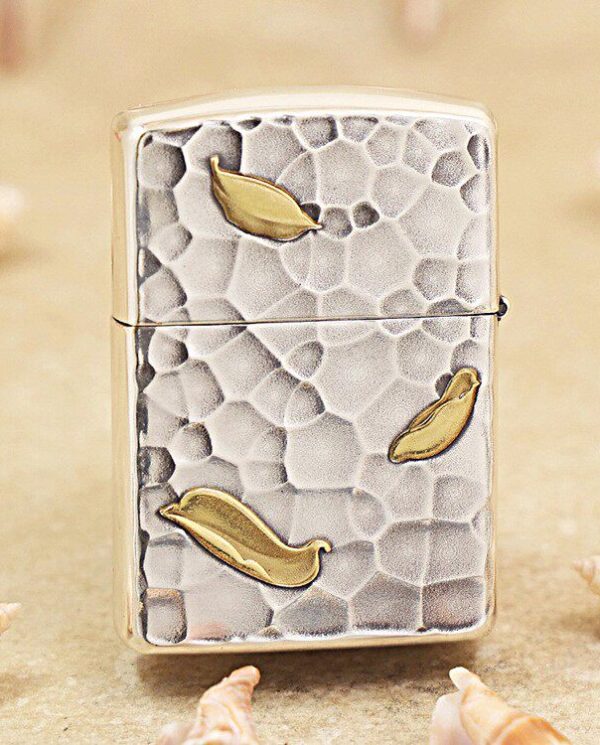 KZ148-01 Metallic lighter with a textured, pebble-like surface and gold leaf accents on a sandy background.