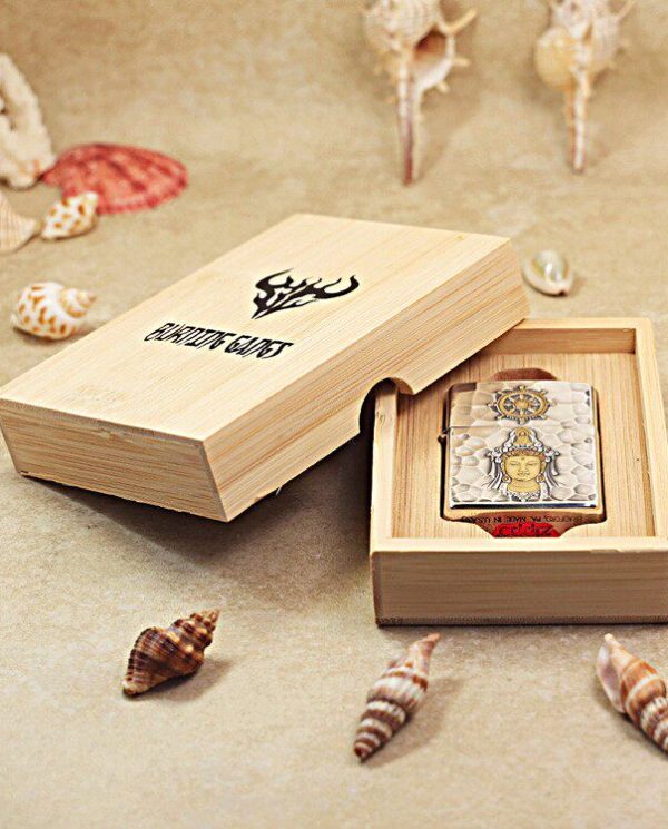 KZ148-04 Open wooden box revealing a decorative metal card with an intricate Buddha-like figure and compass motif, on a sandy beach surface with seashells nearby