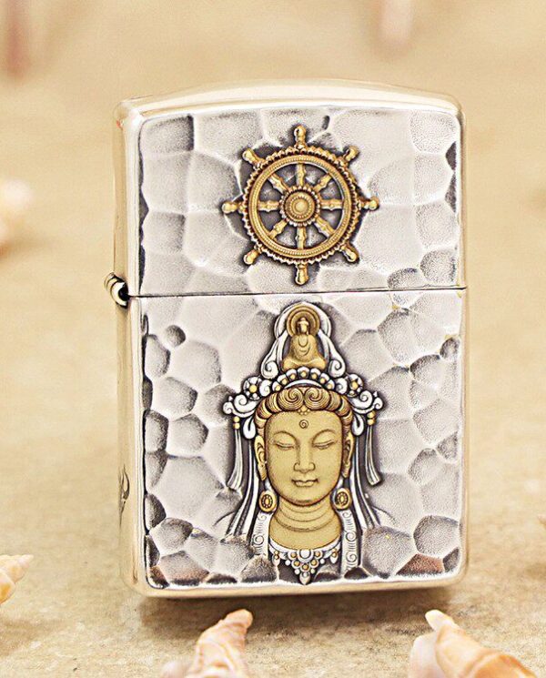 KZ148 Hammered-silver lighter with a gold Buddha relief on the front and a ship’s wheel emblem on the lid, in a beachy setting.