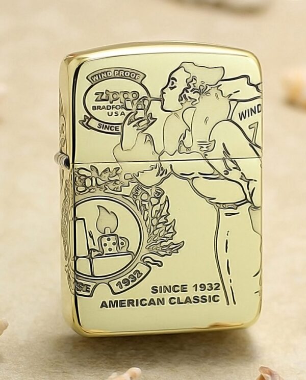 KZ161 Gold Zippo lighter with vintage illustration and the text 'Since 1932' and 'American Classic' displayed on the front, resting on a sandy surface.