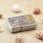 Angled view of the Mermaid Zippo Armor lighter with gold-tone details